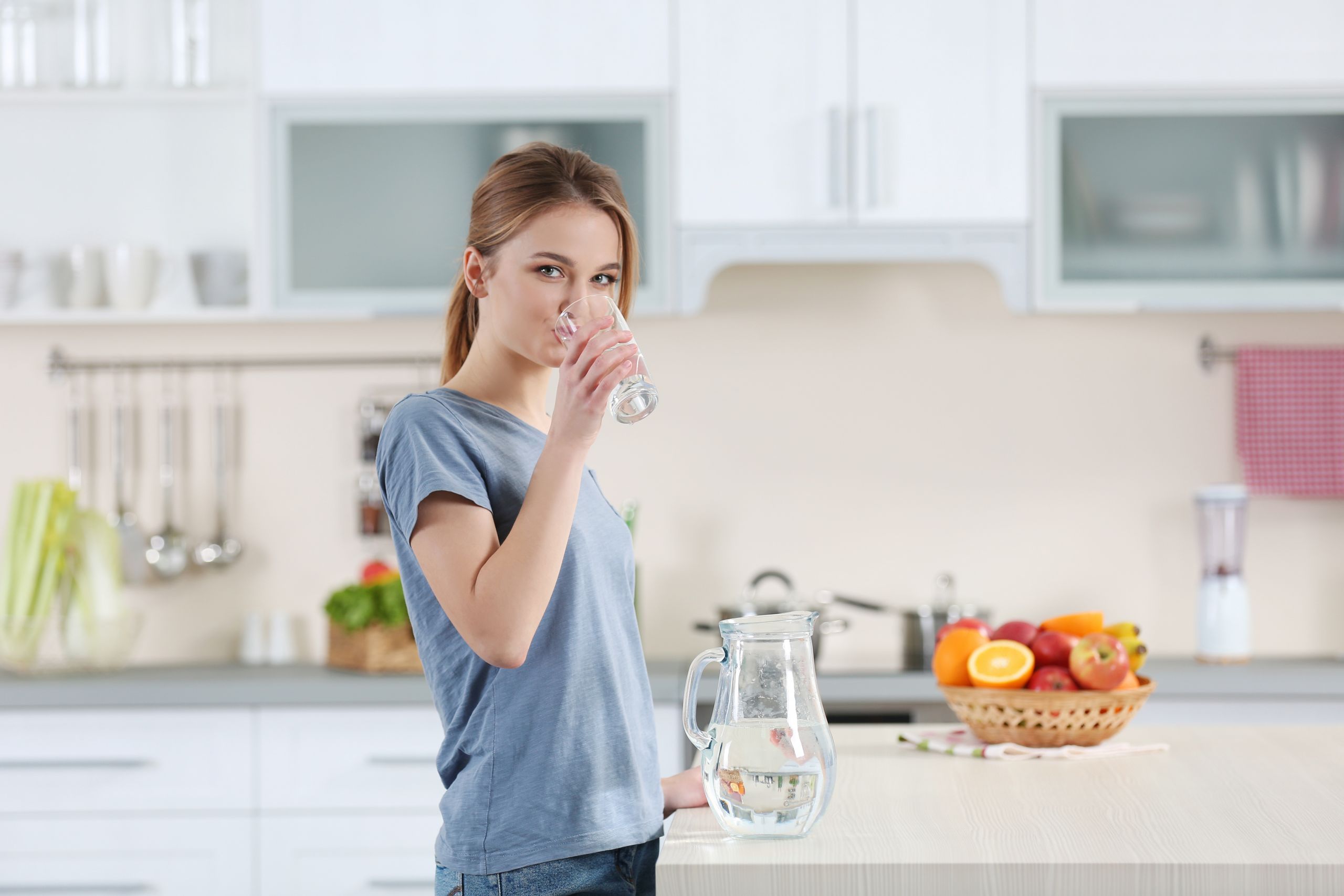 Попить на кухне. Девушка пьет воду. Девушка пьет воду на кухне. Женщина со стаканом воды на кухне. Утро девушка со стаканом воды.